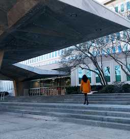 A woman in an orange coat walking up the steps outside CIA Headquarters