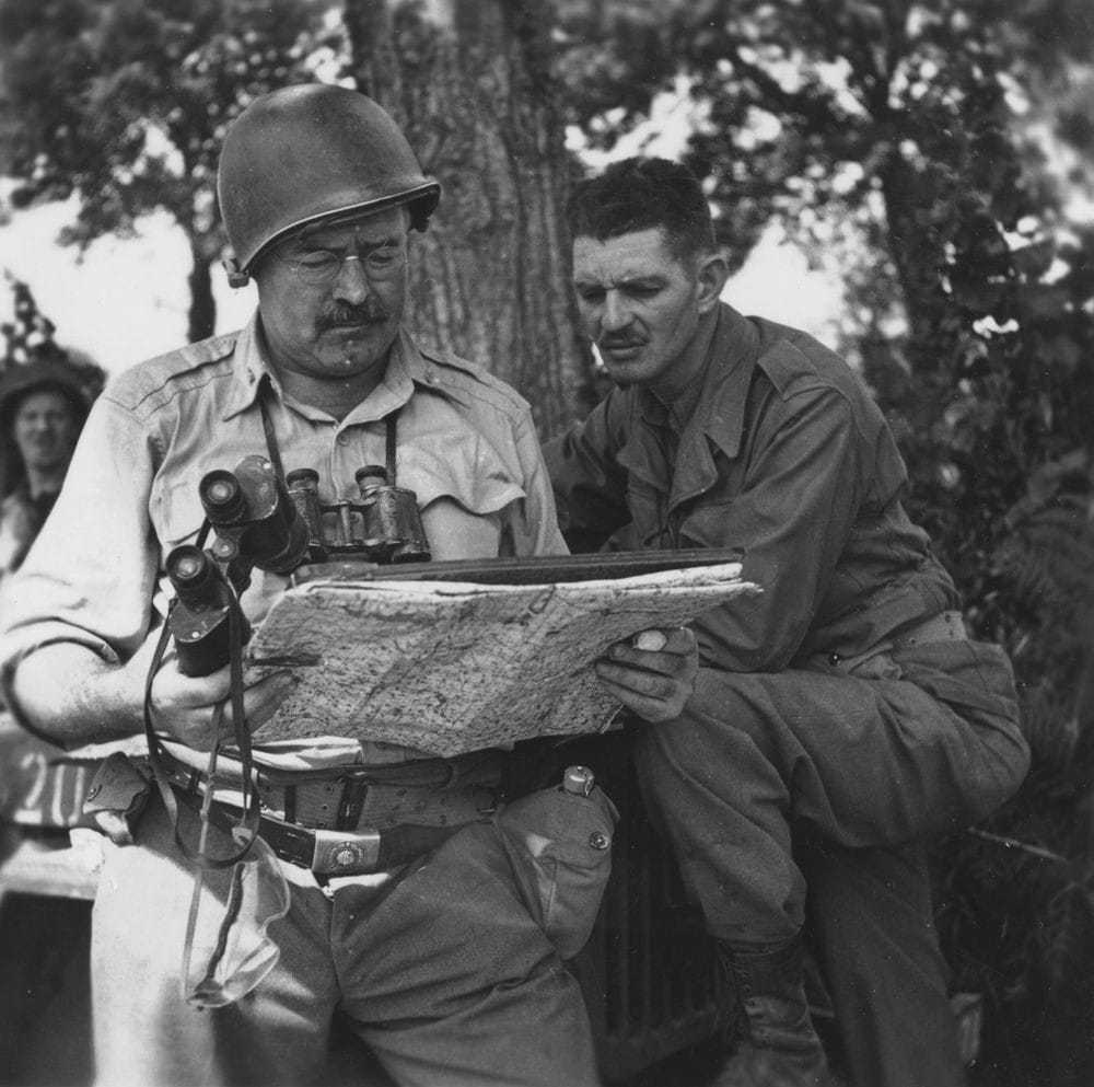 Ernest Hemingway and a soldier look at a map.