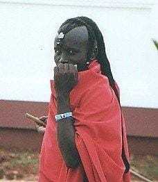 A color photograph taken by Gregg in Africa of a man with a friendly expression wearing an orange robe.