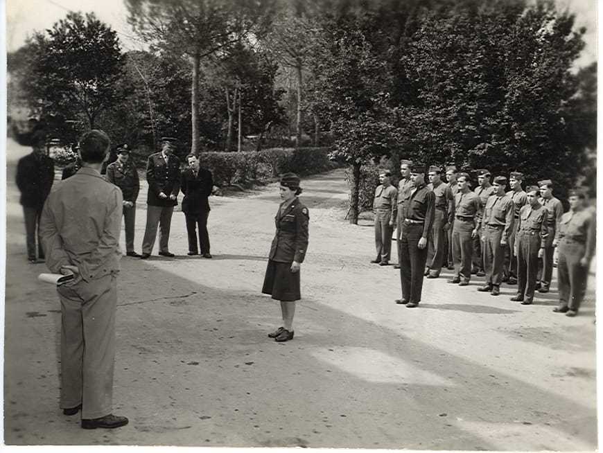 A black and white image of Barbara Lauwers standing at attention in front of her colleagues.