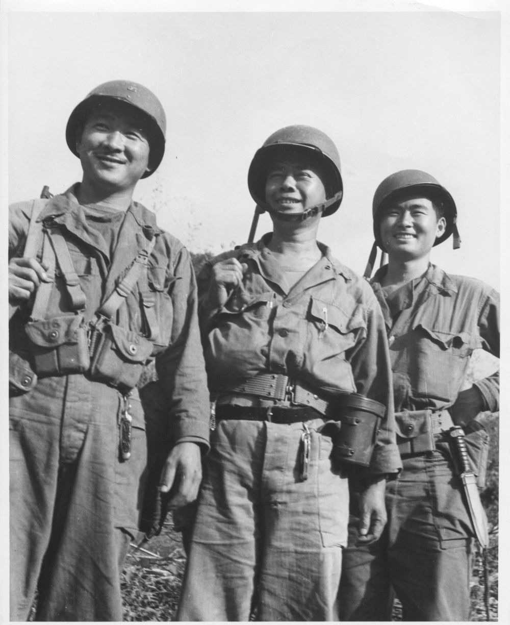 black and white photo of three soldiers standing, looking at the camera.