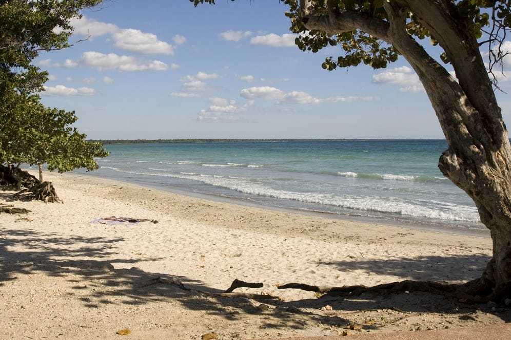 A color photograph of a beach with bright weather and some clouds.