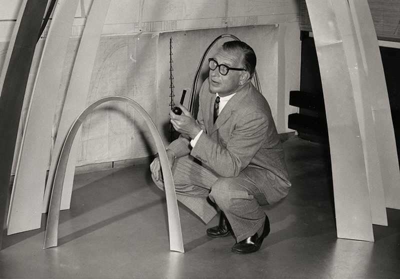 black and white photo of man kneeling under a large domed sculpture.