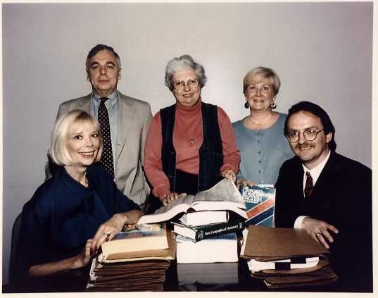 Jeanne Vertefeuille and four others on one side of a wood table covered in books.