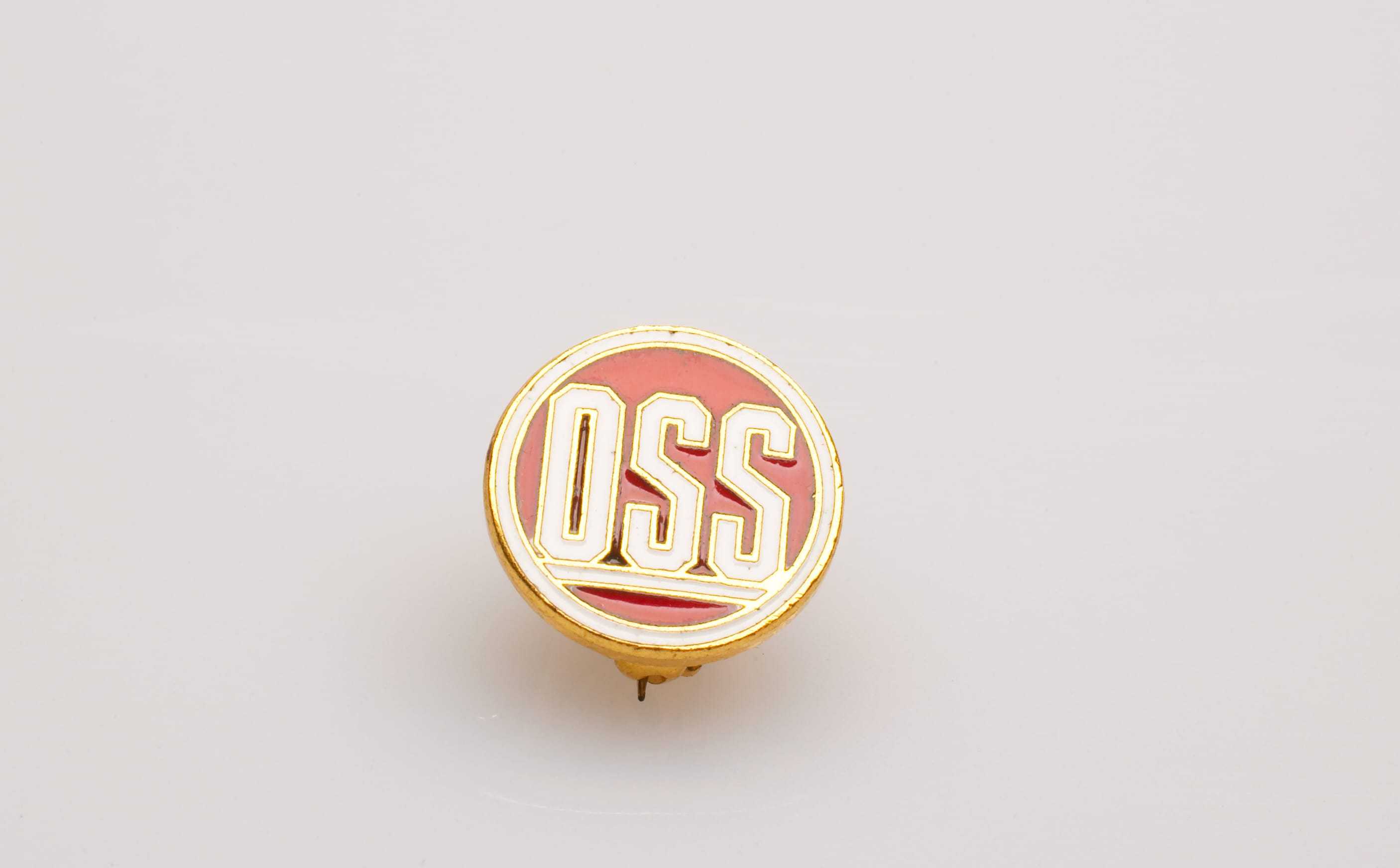 A red, gold, and white OSS pin.
