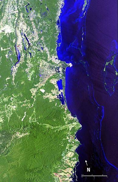 A view of the Belize Barrier Reef, the longest coral reef in the Western and Northern Hemispheres and second largest worldwide (after the Great Barrier Reef of Australia). Running the entire coastline of Belize in Central America, the Belize Barrier Reef supports a large number of patch reefs, shoals, and over 1,000 islands called "cayes." Most of these cayes, and the entire coastline of the country outside of settlements, are protected by huge forests of mangrove. The Turneffe Atoll is shown on the right side of the image. As one of three large coral atolls outside of the reef, it stretches over 48 km (30 mi) long and 16 km (10 mi) wide and is surrounded by one of the most fertile marine ecosystems in the world - a natural nursery for fish, sharks, and crocodiles. Belize City is situated on the outlet of land near the center of the image. It is the largest city in Belize and is the nation's principal port and its financial and industrial hub. Image courtesy of NASA.