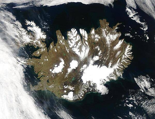 Summer temperatures melt snow and ice on much of Iceland's surface, as shown on this satellite image. The lack of uniform snow cover allows permanent (though shrinking) icefields to show through (particularly Vatnajokull in the southeast), and highlights the island's rugged coastline. Scores of fjords edge the island, resembling feathers waving out into the waters of the northern Atlantic Ocean (bottom) and Greenland Sea (upper left). Photo courtesy of NASA.