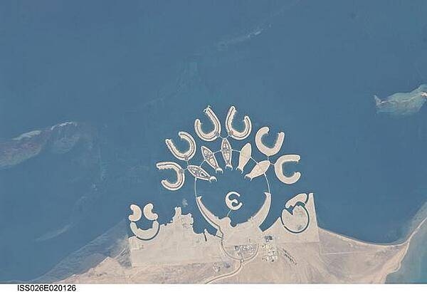 The Durrat Al Bahrain complex is featured in this image photographed from the International Space Station. Set at the southern end of Bahrain Island, at the furthest point from the cities of the kingdom, is this complex of 15 artificial islands designed for residential living and tourism with luxury hotels and shopping malls. Aimed at a cosmopolitan clientele, the Durrat Al Bahrain includes 21 sq km (8 sq mi) of new land for more than 1,000 residences that has been designed as The Islands (six crescent-shaped "atolls" leading off five fish-shaped "petals"). The Crescent at the bottom of the ring is the heart of the complex and features shops, restaurants, hotels, apartments, offices, and schools. The Central Island is dedicated to one, ultra-luxurious hotel. The three, thick, crescent-shaped islands at the lower left make up the Durrat Marina; the area between the Marina and the Crescent is a golf course. Image courtesy of NASA.