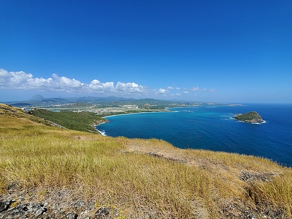 A view from the southern tip of Saint Lucia. The Maria Islands Nature reserve is on the right, the town of Vieux Fort is in the left center, and the Twin Pitons can be seen as bumps on the left horizon.