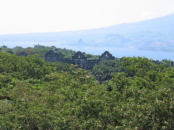 A view of Topside -- the highest area of Corregidor in the Philippines -- taken from the vicinity of the Spanish Lighthouse. Shown are the remains of the "Mile-Long Barracks" barely visible above the trees. In the background are the mountains of Bataan Peninsula.