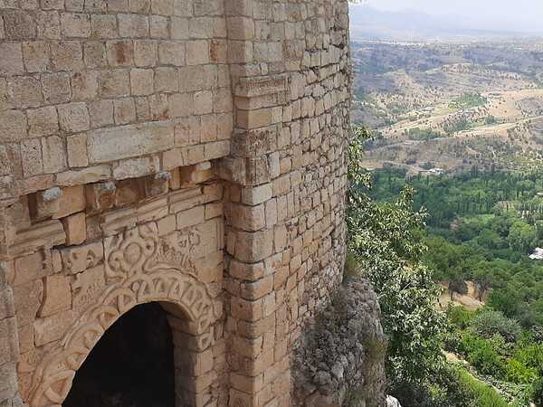 Amadiya or Amedi is a town located on a mesa in the Kurdistan region of northern Iraq. The Bahdinan Gate is the entrance to  the citadel of Al Amadiya, which was built for the defense of Amadiya and as part of a trading route between Amadiya, Mosul, Sinjar, and Baghdad. The gate is 4 m (13 ft) wide with a  large winding stone staircase leading to it and has carvings of unknown people, the sun, and a cord with multiple loops.
