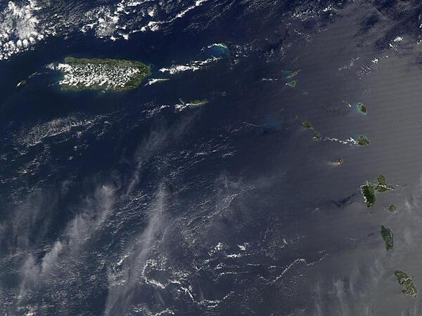A view of Puerto Rico (upper left) and the isles of the Lesser Antilles. The Soufriere Hills Volcano on the island of Montserrat began emitting steam and ash on 9 February 2006. Low-level activity continued for several days. The volcano produced another plume on 20 March 2006, which is captured on this image. The volcano&apos;s pale beige ash plume blows westward over the Caribbean Sea. The red outline shows where the satellite detected a thermal anomaly, an area where the ground surface was significantly hotter than its surroundings. Image courtesy of NASA.