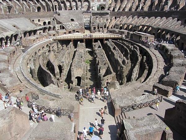 The Colosseum in Rome, Italy was first used in A.D. 80. and it held 50,000 spectators. The name "Colosseum" was introduced in medieval times and referred to a giant statue of Nero that stood nearby. The arena was a wooden floor covered with sand, with rooms and passageways underneath for performers, sets, and animals and it could be flooded to recreate sea battles. Spectator seating was divided into three sections: ordinary people sat in the upper level, the better-off in the middle sections, and the elite in the lower level.